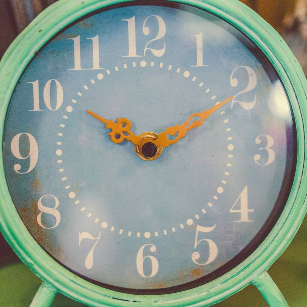Rustic blue alarm clock showing close-up of clock face and time, retro design.
